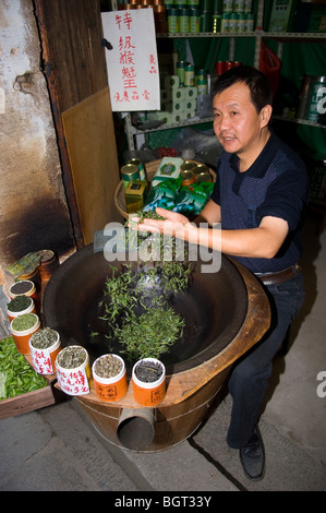 Mann, grüne Teeblätter trocknen und an Touristen zu verkaufen. Hongcun. Anhui Provinz, China. Stockfoto