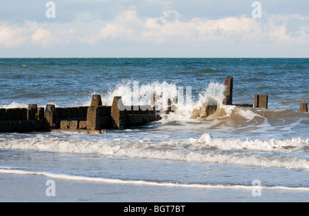 Wellen brechen über eine Buhne am Strand von Mundesley, Norfolk, England, UK Stockfoto