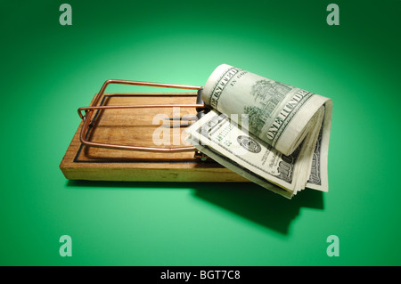 Eine Rolle von Geld sitzt auf einer bewaffneten Mausefalle aus Holz Stockfoto