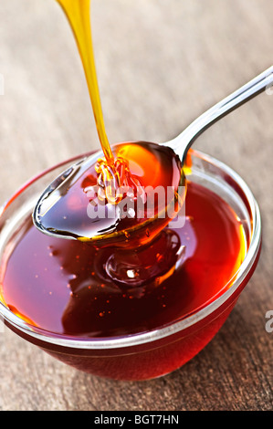 Dicken goldenen Honig beträufeln auf Löffel und Schüssel Stockfoto