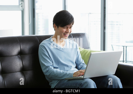 Junger Mann, der auf seinem Laptop arbeitet Stockfoto
