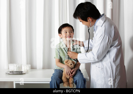 Arzt aufgeben einem kleiner Junge einen Scheck Stockfoto