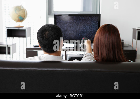 Rückansicht des jungen Paares vor dem Fernseher zu Hause Stockfoto