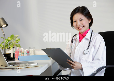 Frau Doktor arbeiten am Schreibtisch und lächelnd Stockfoto
