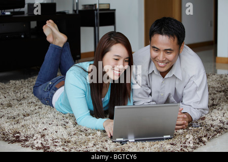 Junges Paar auf Boden arbeiten auf Laptop-computer Stockfoto