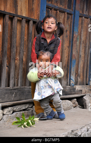 Nepalesische Mädchen, halten ihre jüngere Schwester, beide starren aus Foto Stockfoto