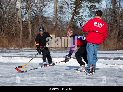 Jungs spielen Eishockey auf einem zugefrorenen Teich Stockfoto