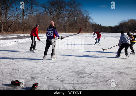 Jungs spielen Eishockey auf einem zugefrorenen Teich Stockfoto