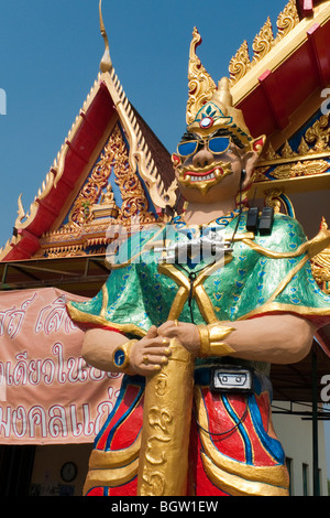 Ein Dämon mit Sonnenbrille, Rolex-Uhr und eine Kamera vor Wat Bang Yai, Nonthaburi, Ban Nak Kiao, Bangkok, Thailand, Asien. Stockfoto