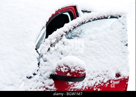 Rotes Auto unter einer frischen Schneedecke Stockfoto