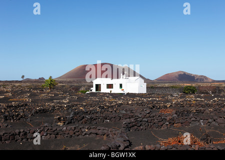 Weiße Haus im Großraum La Geria Wein, Vulkane in der Ferne, von links, Caldera Colorada, Montaña Ortiz, Lanzarote, Cana Stockfoto