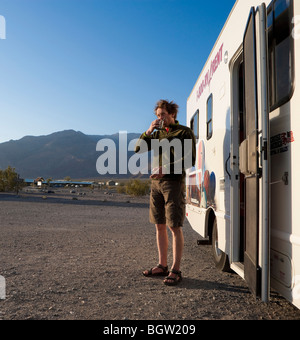 Mann stehend und trinken vor ein Freizeitfahrzeug, Death Valley Nationalpark, Kalifornien, USA Stockfoto