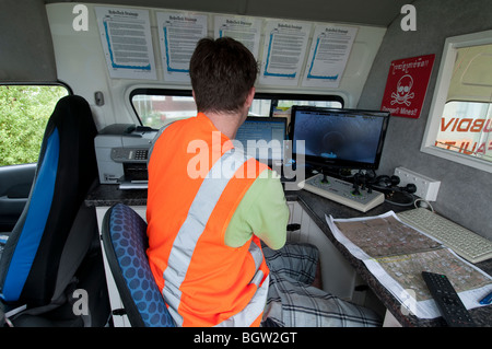 Junger Mann in van guiding remote Video Kamera durch unterirdische Leitungen betrachten live Kamera-Aufnahmen auf Leinwand Stockfoto