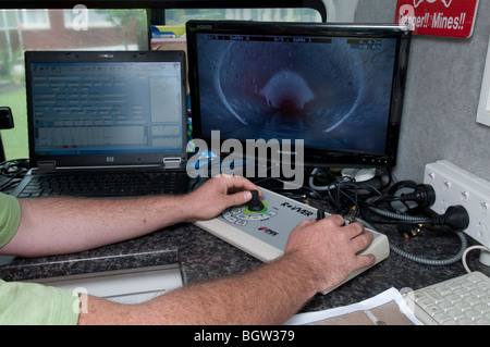 Junger Mann in van guiding remote Video Kamera durch unterirdische Leitungen betrachten live Kamera-Aufnahmen auf Leinwand Stockfoto