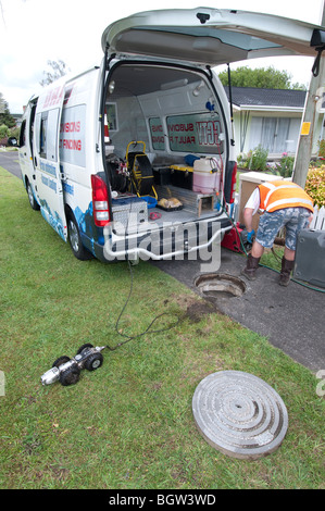 Junger Mann in van guiding remote Video Kamera durch unterirdische Leitungen betrachten live Kamera-Aufnahmen auf Leinwand Stockfoto