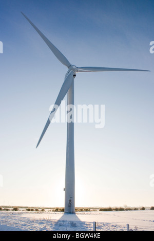 Windkraftanlage im Schnee dominiert eine flache Fenland Landschaft und Silhouette gegen den Sonnenaufgang in einer blauen Winterhimmel Stockfoto