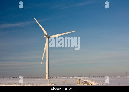 Windkraftanlage im Schnee gegen blauen Winterhimmel dominiert eine flache Fenland-Landschaft Stockfoto