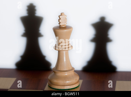 Schachfigur - ein weißer König auf einem Schachbrett. Schatten von anderen Schachfiguren können im Hintergrund zu sehen. Stockfoto