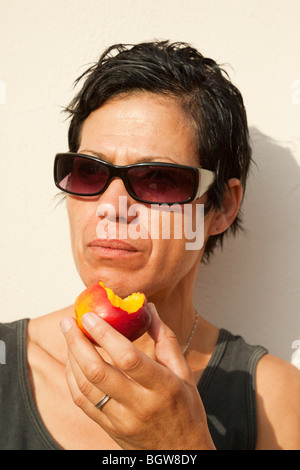 Frau, Essen einen Pfirsich Stockfoto