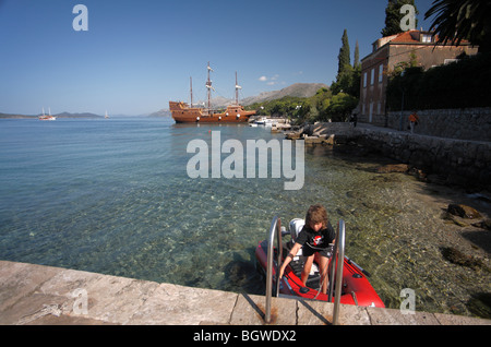 Kleiner Junge Landung auf Steg im Schlauchboot Replica Galeone Tirena Donje Celo Hafen, Kolocep, Süd-Dalmatien Kroatien Stockfoto