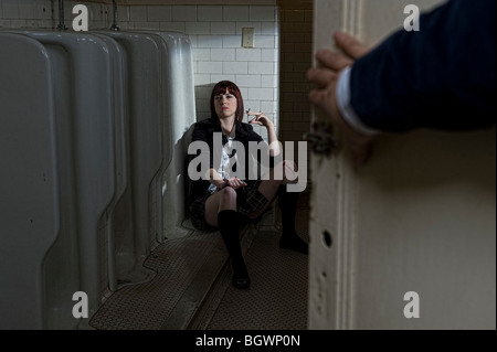 Frau in Schule einheitliche Posen mit Zigarette im institutionellen Bad Stockfoto