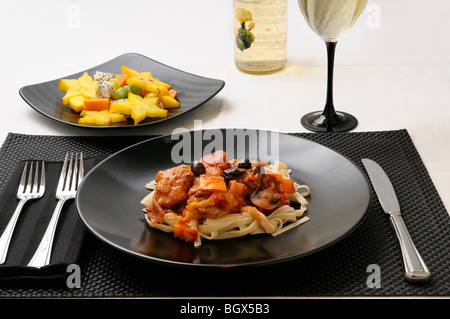 Tabelle Einstellung mit Teller von Huhn Marengo und Obstsalat und Weißwein Stockfoto