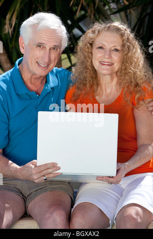 Ein Senior zog sich Mann und Frau Paar sitzt außen mit einem Wireless-Laptop-Computer im Internet surfen. Stockfoto