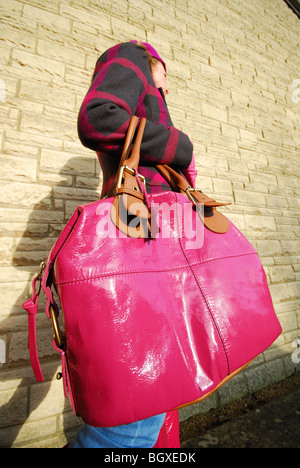 Eine Frau, die eine übergroße rosa Lederhandtasche trägt. Stockfoto