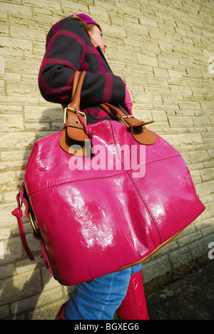 Eine Frau, die eine glänzende, rosa, übergroße Handtasche trägt. Stockfoto