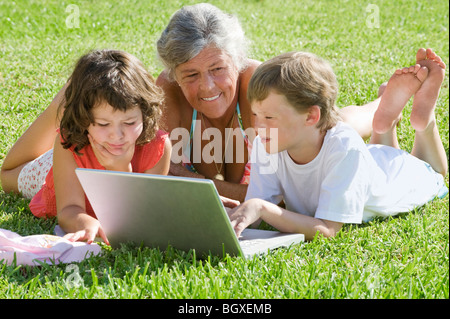 Ältere Frau mit Kindern auf laptop Stockfoto