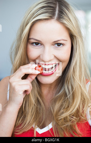 Junge Frau knabbert an Tomaten Stockfoto