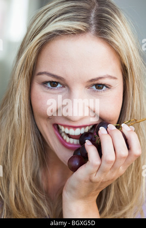 Junge Frau essen Trauben Stockfoto