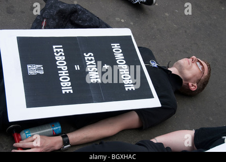 Paris, Frankreich - Gay Rights Aktivists of Act up-Paris protestieren gegen Homophobie, Mann, der auf Gehsteig IDAHOT gegen Sexismus, Lesbophobie legt Stockfoto