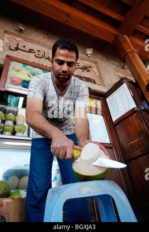 Verkaeufers Kokosmilch bereitet aus seinem Stall auf die Gewürz-Souk in Deira, Dubai, Vereinigte Arabische Emirate. Stockfoto