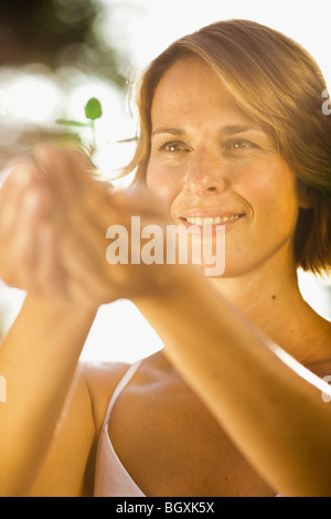 Frau mit Bäumchen mit beiden Händen Stockfoto