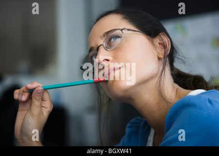 Frau denken, Stift wegsehen, im Mund Stockfoto