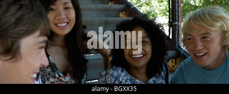 Gruppe von jungen Erwachsenen Freunden im Freien zu sitzen, zu plaudern und zu Lächeln Stockfoto