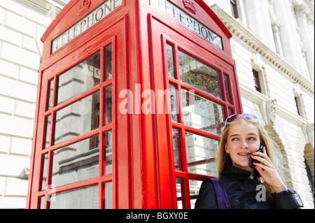 Frau neben Telefonzelle auf ihrer Zelle Stockfoto