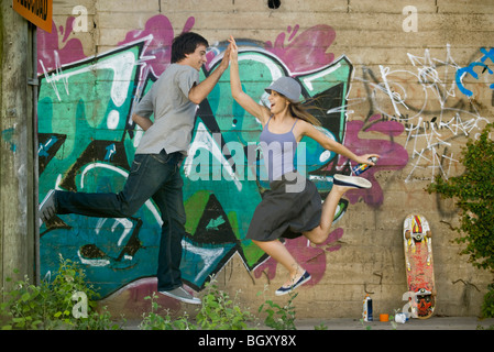 Junges Paar springen für High-Five Stockfoto