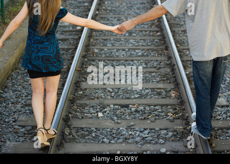 Junges Paar Hand in Hand gehen auf Gleis, Rückansicht Stockfoto