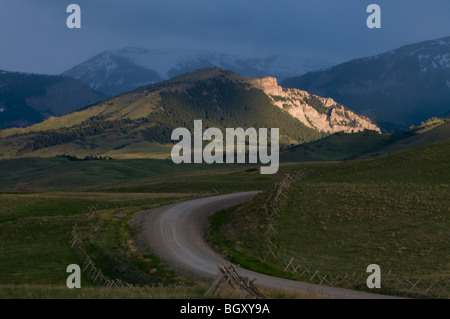 Landstraße und Berge gebadet in dramatischen Sonnenaufgang-Rocky Mountain Front, Montana Stockfoto
