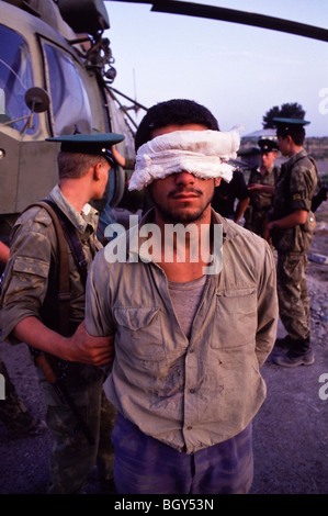 Russische Soldaten bewachen einen mit verbundenen Augen tadschikischen Gun Schmuggler neben einem russischen Mi-8 Hubschrauber in Pyandzh, Tadschikistan Stockfoto