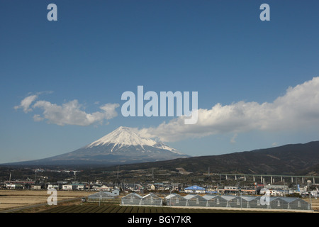 Mount Fuji, hinter einer Kulisse von landwirtschaftlichen und industriellen Landschaft, von einem Shinkansen-Hochgeschwindigkeitszug Fenster, Japan gesehen. Stockfoto