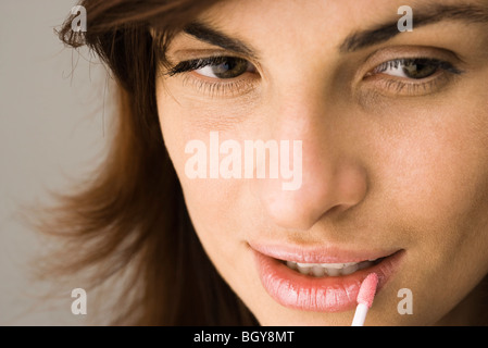 Junge Frau Lipgloss mit Pinsel auftragen Stockfoto