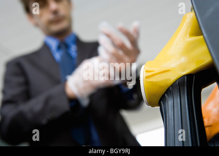 Mann, der auf Einweg-Handschuhe Fahrzeug tanken wird vorbereitet Stockfoto