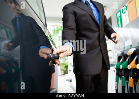 Gut gekleideter Mann ins Auto nach Betankung an Tankstelle Stockfoto