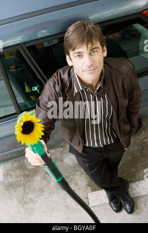 Mann an der Tankstelle halten Gasdüse mit Sonnenblumen entstehende Ende Stockfoto