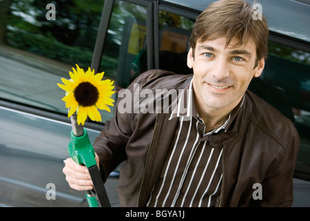 Mann an der Tankstelle halten Gasdüse mit Sonnenblumen entstehende Ende Stockfoto