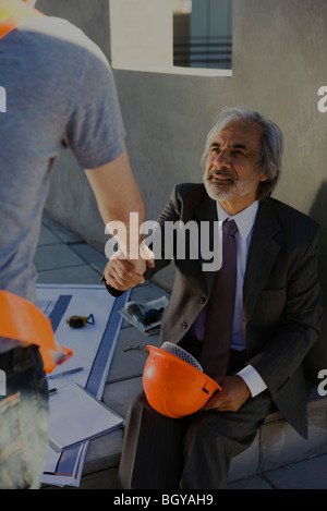 Architekt Händeschütteln mit Bauarbeiter auf der Baustelle zugeschnitten Stockfoto