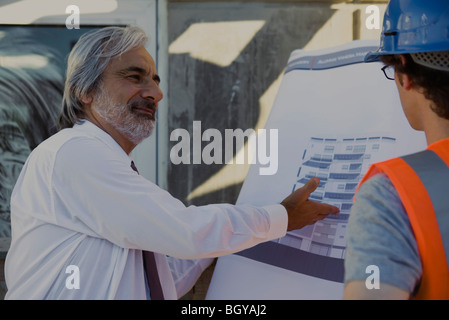 Architekten, die Details der Blaupause, Bauarbeiter zu erklären Stockfoto